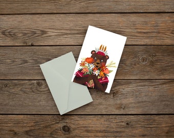 Greeting card depicting a bear holding a bouquet of flowers