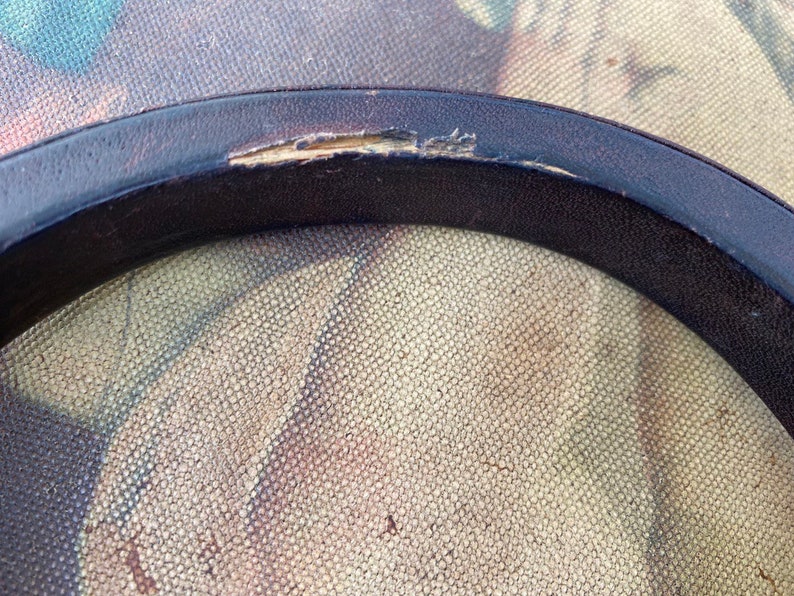 May include: Close-up of a black leather ring with a small tear in the leather.