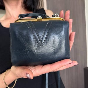 Pequeño bolso de mano de piel negra, estilo años 70. Cartera de noche con correa larga.