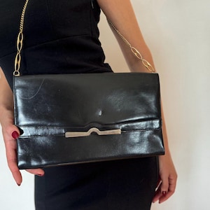 Monedero vintage negro de los años 60. Cartera de mano pequeña de piel con correa larga.