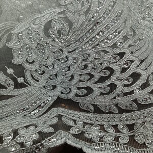 May include: White lace fabric with silver sequins and a floral pattern.