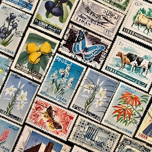 Op de afbeelding: Een verzameling vintage postzegels uit Libanon, met verschillende ontwerpen. De postzegels tonen afbeeldingen van fruit, bloemen, vlinders en architectonische bezienswaardigheden. De postzegels zijn in verschillende kleuren, waaronder blauw, groen, rood en geel.