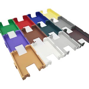 May include: A collection of colorful plastic trays in various hues, including green, red, blue, and brown. Each tray has a rectangular shape with a cutout section and a white insert. The trays are arranged in a grid-like pattern.