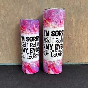 May include: Two stainless steel tumblers with a white center band and a swirling pink, purple, and gold design. The text "I'M SORRY Did I Roll MY EYES Out Loud?" is printed in black on the white band.