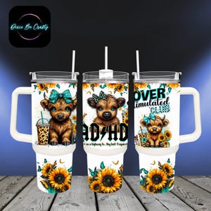 May include: White insulated tumbler with a handle, featuring a brown Highland cow with a teal bow, sunflowers, and butterflies. One tumbler has the text "ADHD" and another says "OVER STIMULATED CLUB". Includes a straw and a lid.