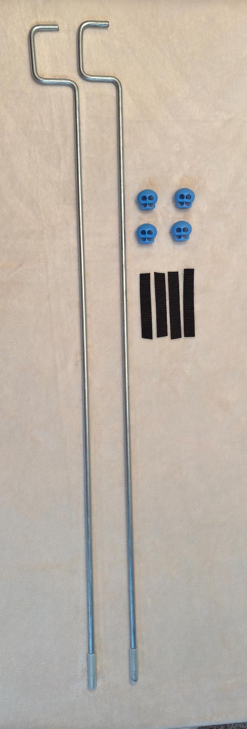 May include: Two silver metal tent poles with black straps and blue plastic caps.