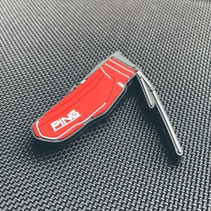 Könnte beinhalten: Ein roter, golfbagförmiger Golfball-Marker mit dem Wort "PING" in weißen Buchstaben.