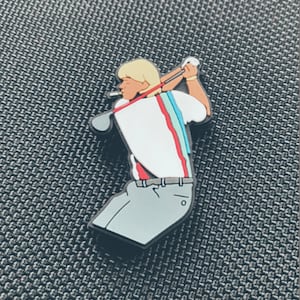 Könnte beinhalten: Eine Cartoon-Golfer-Figur mit blonden Haaren, die ein weißes Hemd mit roten und blauen Streifen, graue Hosen und einen roten Gürtel trägt. Der Golfer hält einen Golfschläger und befindet sich in einer Schwungposition.