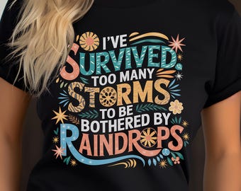 May include: Black t-shirt with a colorful graphic that says "I've survived too many storms to be bothered by raindrops".