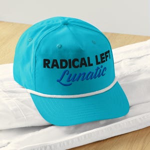 Könnte beinhalten: Eine türkisblaue Baseballkappe mit weißem Seilbesatz. Die Kappe hat einen schwarzen gestickten Text, der "RADICAL LEFT Lunatic" in einer stilisierten Schriftart lautet.