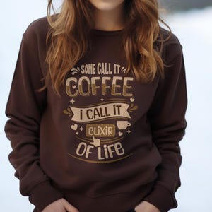 Peut inclure: Sweat-shirt marron avec le texte "Some call it coffee, I call it elixir of life" imprimé sur le devant.