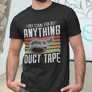 Puede incluir: Una camiseta negra con un gráfico de estilo retro que dice "Puedo arreglar cualquier cosa, ¿dónde está la cinta adhesiva?" El gráfico presenta un rollo de cinta adhesiva con un fondo de rayas de arcoíris.