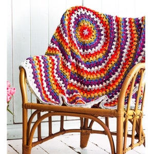 May include: A colorful crocheted throw blanket with a circular pattern in shades of orange, red, purple, and white. The blanket is draped over a wooden chair.