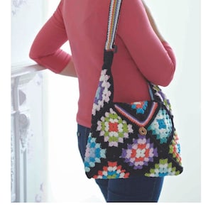 Könnte beinhalten: Eine schwarze Häkel-Tasche mit einem bunten Granny-Square-Muster. Die Tasche hat einen langen, mehrfarbigen Riemen und einen Verschluss aus Holz.