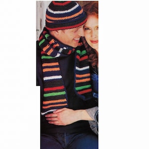 May include: A crocheted hat and scarf set with black, white, red, orange, and green stripes. The hat has a folded brim and the scarf is long and narrow.