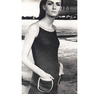 Könnte beinhalten: Ein schwarzes, ärmelloses Häkelkleid mit weißen Verzierungen und zwei aufgesetzten Taschen. Das Kleid ist figurbetont und hat einen runden Ausschnitt.