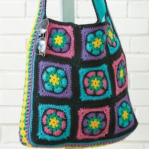 May include: A black crocheted tote bag with a colourful floral pattern. The bag has a long strap and is made of multiple squares with different coloured flowers.
