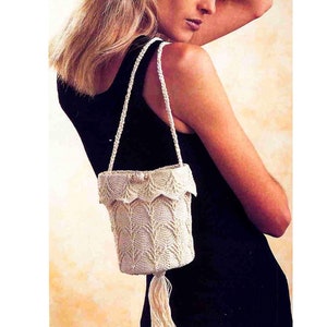 May include: A white crocheted handbag with a tassel and a scalloped top. The bag has a long strap and is worn over the shoulder.