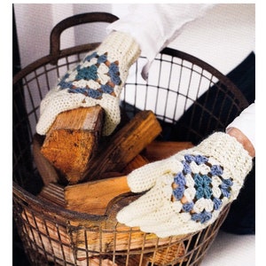 May include: A pair of white crocheted gloves with blue and green granny squares. The gloves are being used to hold a basket of firewood.
