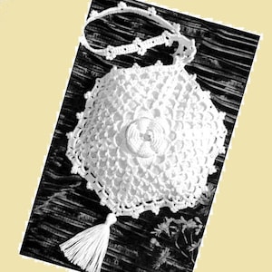 May include: White crocheted handbag with a tassel and a delicate floral design. The bag has a shoulder strap and a button closure.