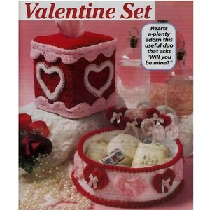 May include: A Valentine's Day set featuring a red and white crocheted tissue box cover with heart cutouts and a matching round container. The set includes the text "Valentine Set" and "Hearts a-plenty adorn this useful duo that asks 'Will you be mine?'".