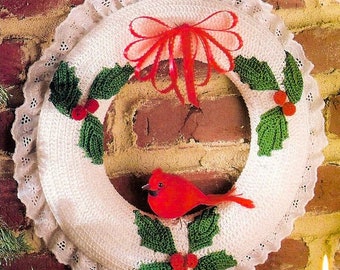 May include: A white crocheted Christmas wreath with a red bow, green holly leaves, red berries, and a red cardinal bird.
