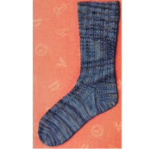 Può includere: Un calzino blu lavorato a maglia con un motivo strutturato. Il calzino presenta sfumature di blu e grigio, con un polsino a coste e un motivo a righe sul piede. Il calzino è progettato per il comfort e il calore.
