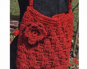 May include: A red crocheted handbag with a large flower design on the front. The bag has a long strap and is made of a thick, textured yarn.