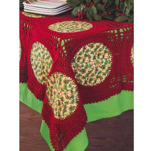 Puede incluir: Mantel de mesa de crochet rojo con un patrón floral verde y blanco en el centro. El mantel tiene una forma cuadrada con esquinas redondeadas y un borde festoneado.