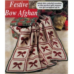 May include: A cream-colored crocheted afghan with a repeating pattern of red bows within square frames. The afghan is trimmed with a dark green border. The text "Festive Bow Afghan" is displayed at the top.