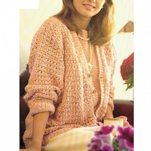 Puede incluir: Un cárdigan de punto de ganchillo rosa y una blusa a juego con un collar de perlas. El cárdigan tiene cierre de botones y mangas largas.