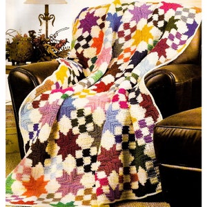 May include: A colourful crocheted throw blanket with a patchwork design featuring stars and squares in various shades of pink, purple, blue, green, yellow, orange, and brown.