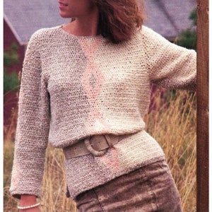 Könnte beinhalten: Ein gehäkelter Pullover mit einem diagonalen Streifenmuster in Beige-, Rosa- und Weißtönen. Der Pullover hat einen runden Halsausschnitt und lange Ärmel. Ein brauner Ledergürtel mit einer großen silbernen Schnalle wird um die Taille getragen.