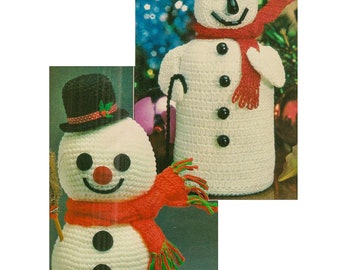 May include: Two crocheted snowmen, one with a red scarf and a broom, the other with a red scarf and a cane. Both snowmen have black top hats and black buttons.