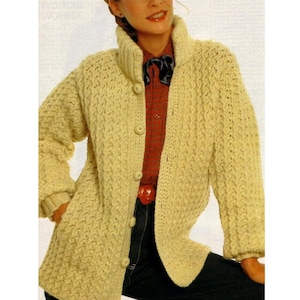 May include: A cream-coloured crocheted cardigan with a high collar and button fastening. The cardigan features a textured stitch pattern and is shown being worn by a model.