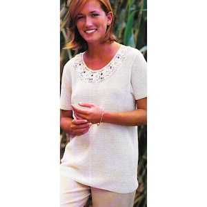 May include: White crochet top with a crocheted floral neckline. The top has short sleeves and a loose fit.