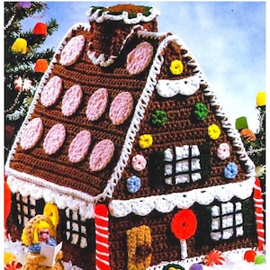 Puede incluir: Una casa de jengibre de crochet decorada con dulces, incluyendo gomitas, piruletas y bastones de caramelo. La casa tiene una valla blanca y una pequeña ventana con un patrón a cuadros.