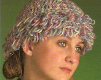 May include: A woman wearing a crocheted hat with a multi-colored design of pink, blue, and white yarn.