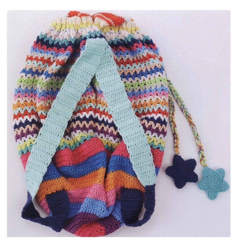 May include: A colorful crocheted backpack with blue straps and two star-shaped charms. The backpack is made with a variety of colors, including red, orange, yellow, green, blue, purple, and pink.
