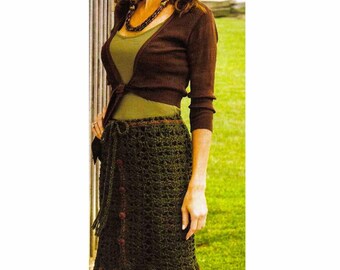 Peut inclure: Une jupe en crochet verte avec des bordures et des boutons marrons. La jupe a un ourlet festonné et est portée avec un cardigan marron et un débardeur vert.