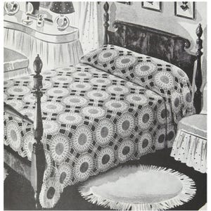 Puede incluir: Una colcha de ganchillo blanca con un patrón circular sobre un marco de cama de madera. La colcha está hecha de puntadas delicadas y de encaje y presenta un diseño repetitivo de círculos.