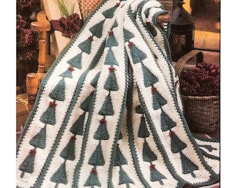 May include: A crocheted throw blanket with a repeating pattern of green Christmas trees with red ornaments. The blanket is draped over a wooden chair.