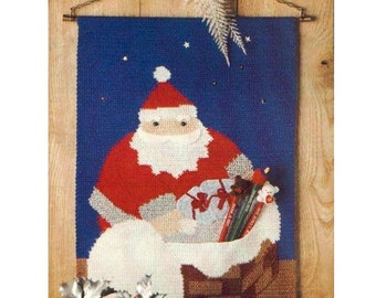 Può includere: Un arazzo natalizio blu e bianco con Babbo Natale con la barba bianca, che indossa un abito rosso e porta un sacco di regali. È in piedi davanti a un camino con un cielo notturno stellato sullo sfondo.