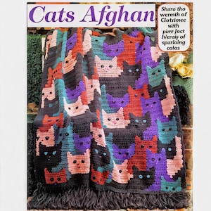 Peut inclure: Une couverture afghane au crochet avec un motif répété de visages de chats de différentes couleurs, dont rose, violet, turquoise et orange, sur un fond gris foncé. La couverture a une bordure à franges et le texte "Cats Afghan" est visible.