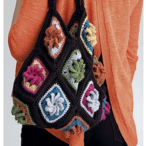 May include: A black crocheted tote bag with colorful flower motifs. The bag has a square shape and is made with a variety of yarn colors, including pink, green, blue, orange, and brown.