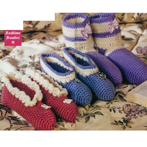 May include: A set of four crocheted slippers in pink, purple and white. The slippers have a decorative trim and are labelled "Bedtime Booties".