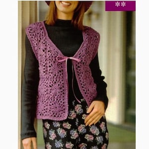 Peut inclure: Un gilet en crochet violet avec un nœud à l'avant. Le gilet a un motif ajouré avec un design floral.