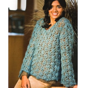 Könnte beinhalten: Ein hellblauer Häkelpullover mit einem Spitzenmuster. Der Pullover hat einen V-Ausschnitt und lange Ärmel.