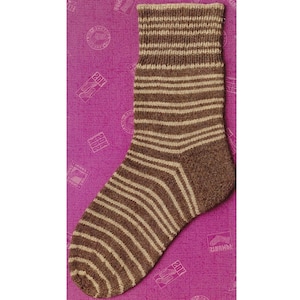 May include: A brown and beige striped sock. The sock is knit with horizontal stripes and has a ribbed cuff. The heel and toe are a solid brown color. The sock is displayed on a purple background.