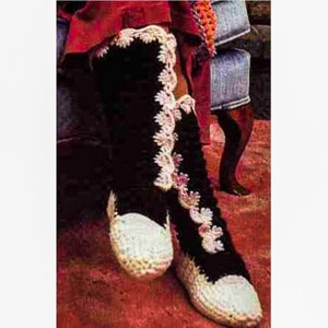 May include: Crocheted black and white slippers with a white lace trim. The slippers are worn on a person's feet.